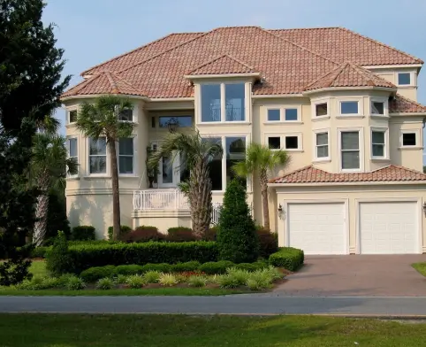 A large house with a driveway and bushes around it.