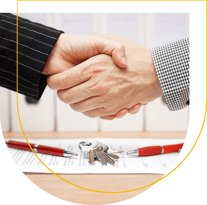 Two people shaking hands over a table with keys.