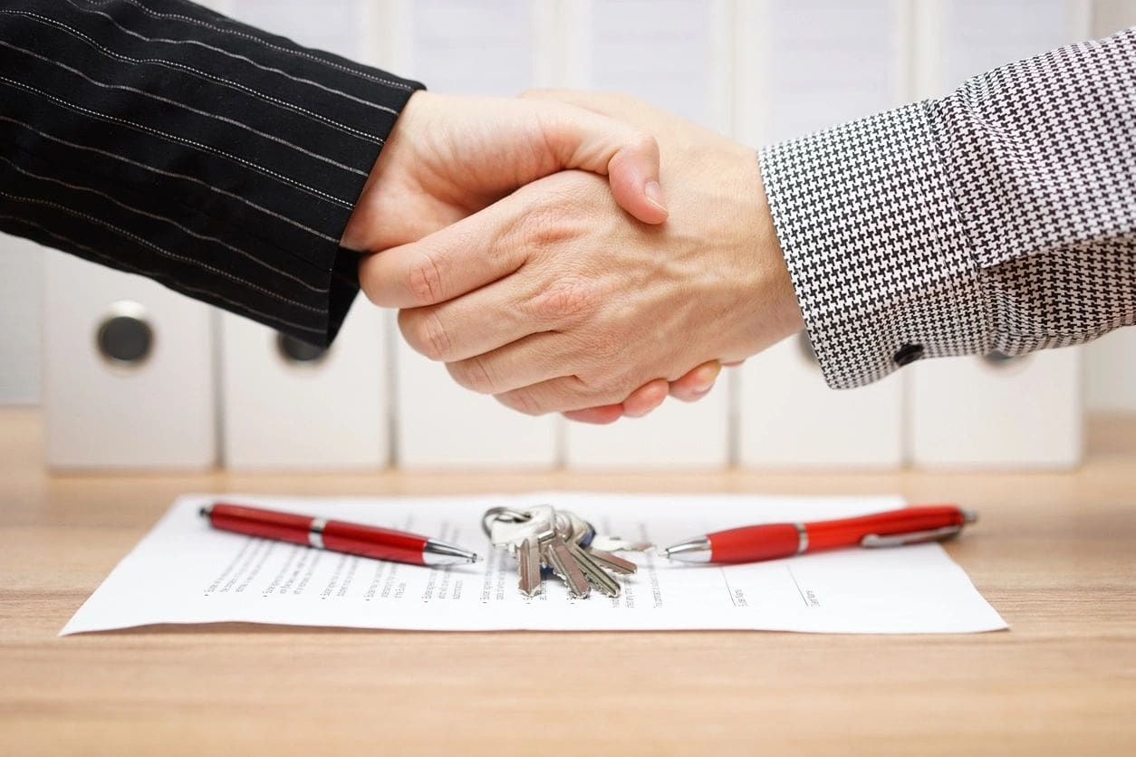 Two people shaking hands over a contract