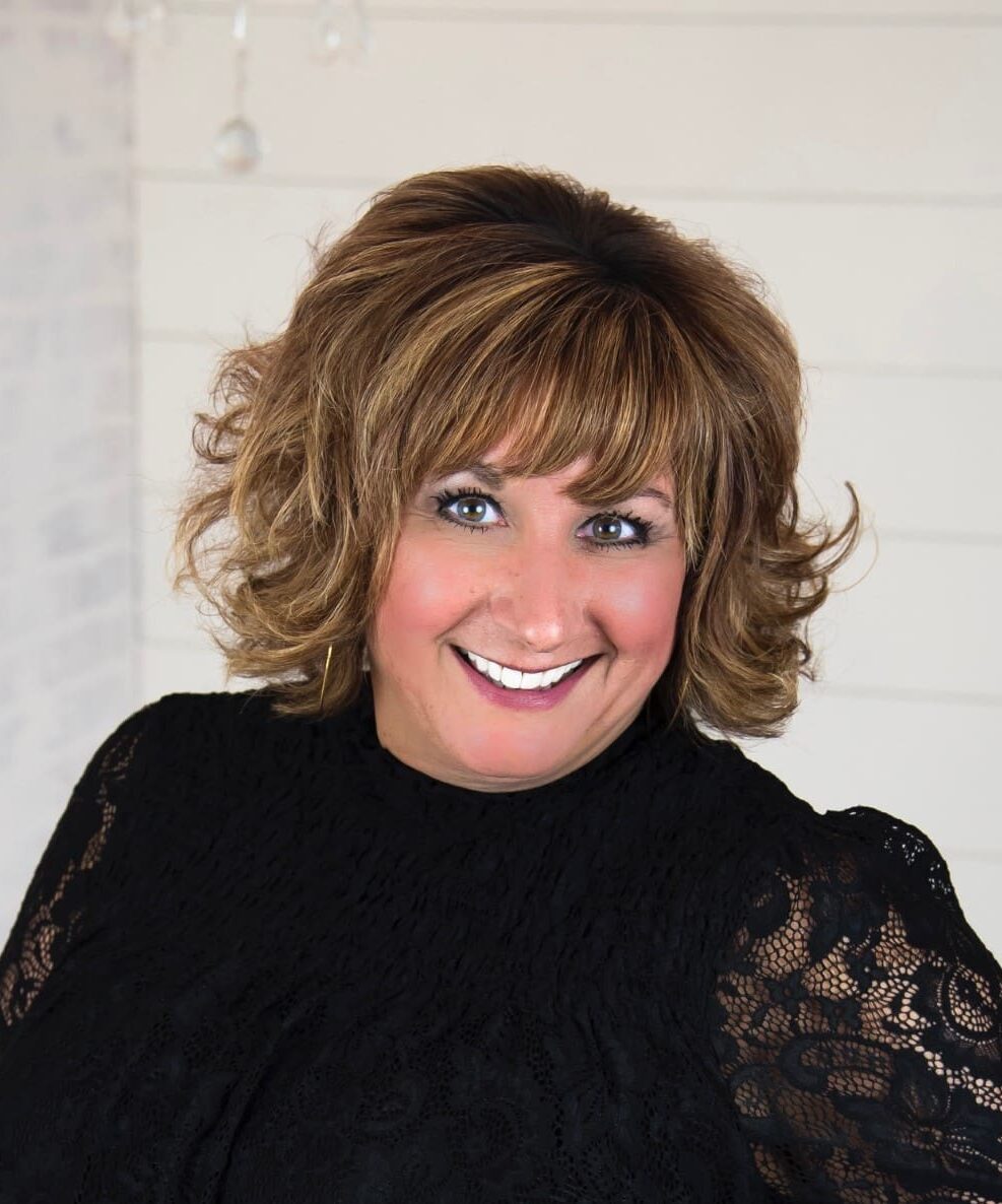 A woman with brown hair and blue eyes wearing black.