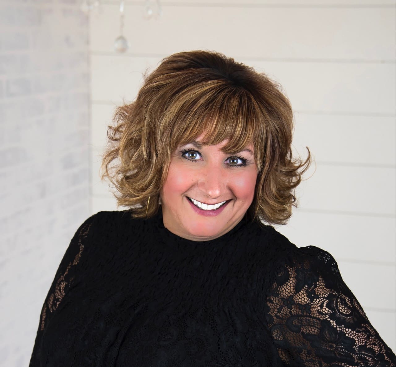 A woman with brown hair and blue eyes wearing black.