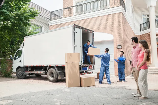 Three men unloading boxes from a moving truck.