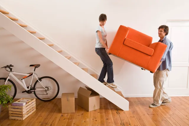 A man carrying furniture up the stairs